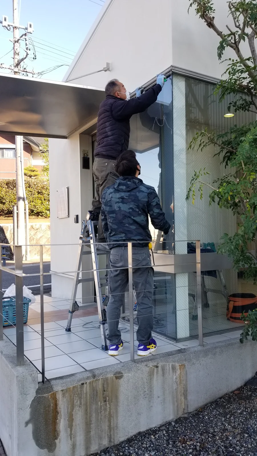 複数人で新しい大型ガラスを開口へ取り付けている作業