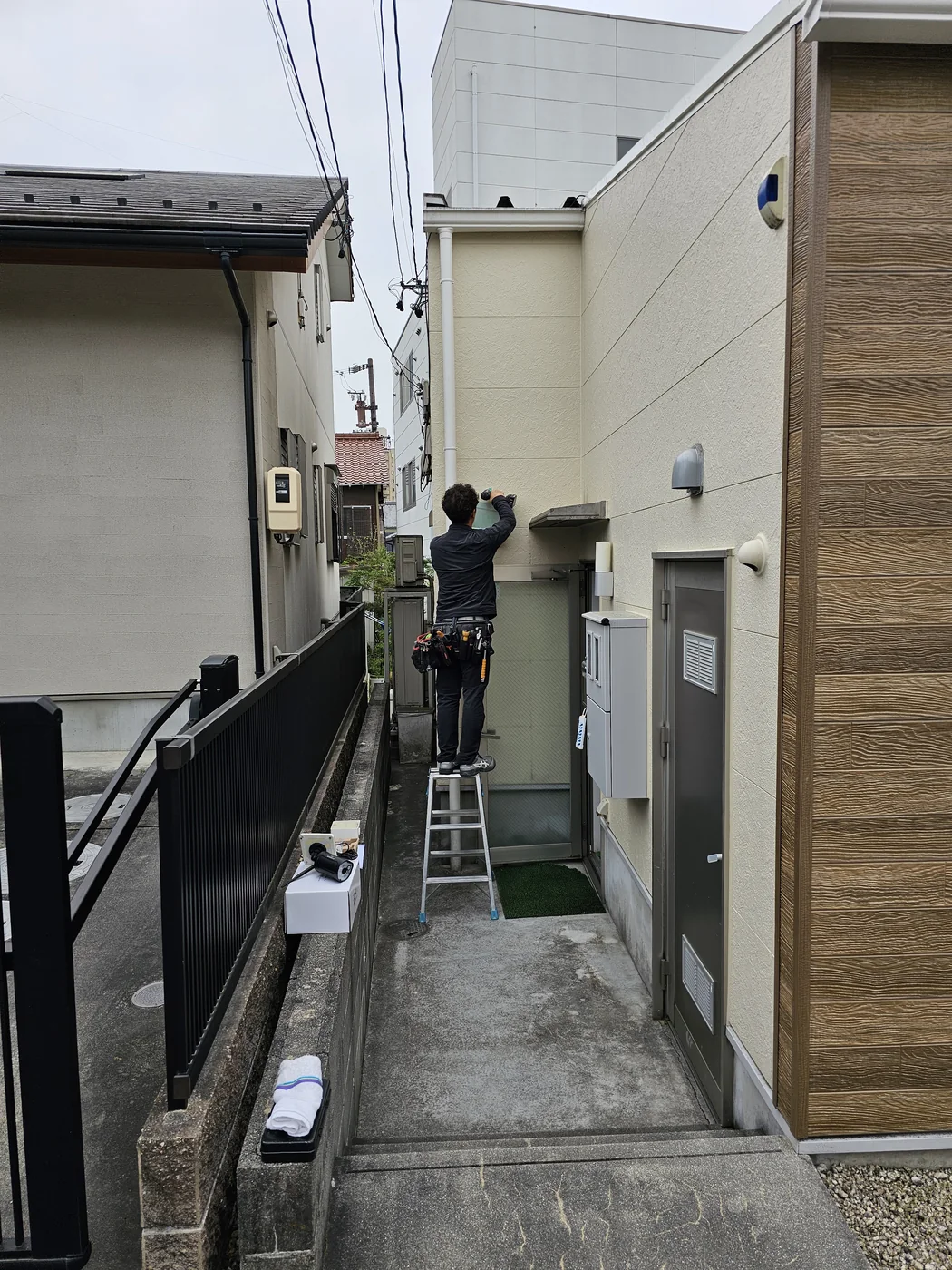 作業員が外壁でマスプロ電工製ワイヤレス防犯カメラの設置位置と撮影方向を確認している作業