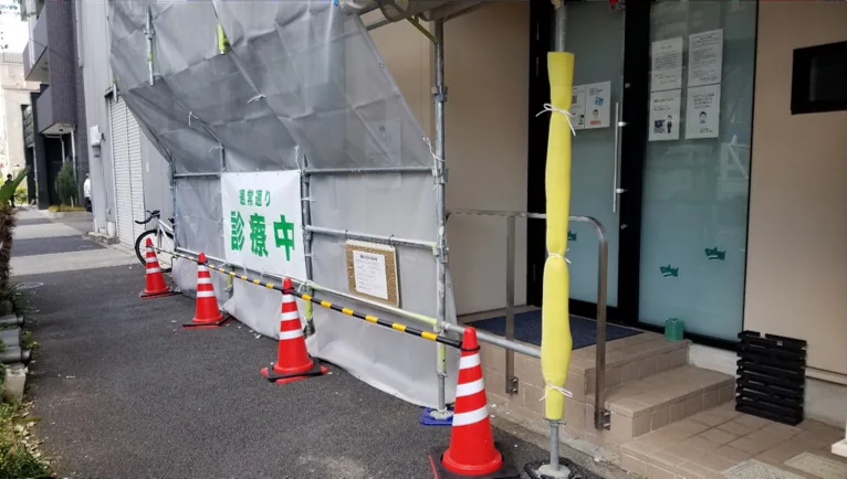 足場へ診察中の表示を掲示し、入口前にコーンとバーを設置した様子